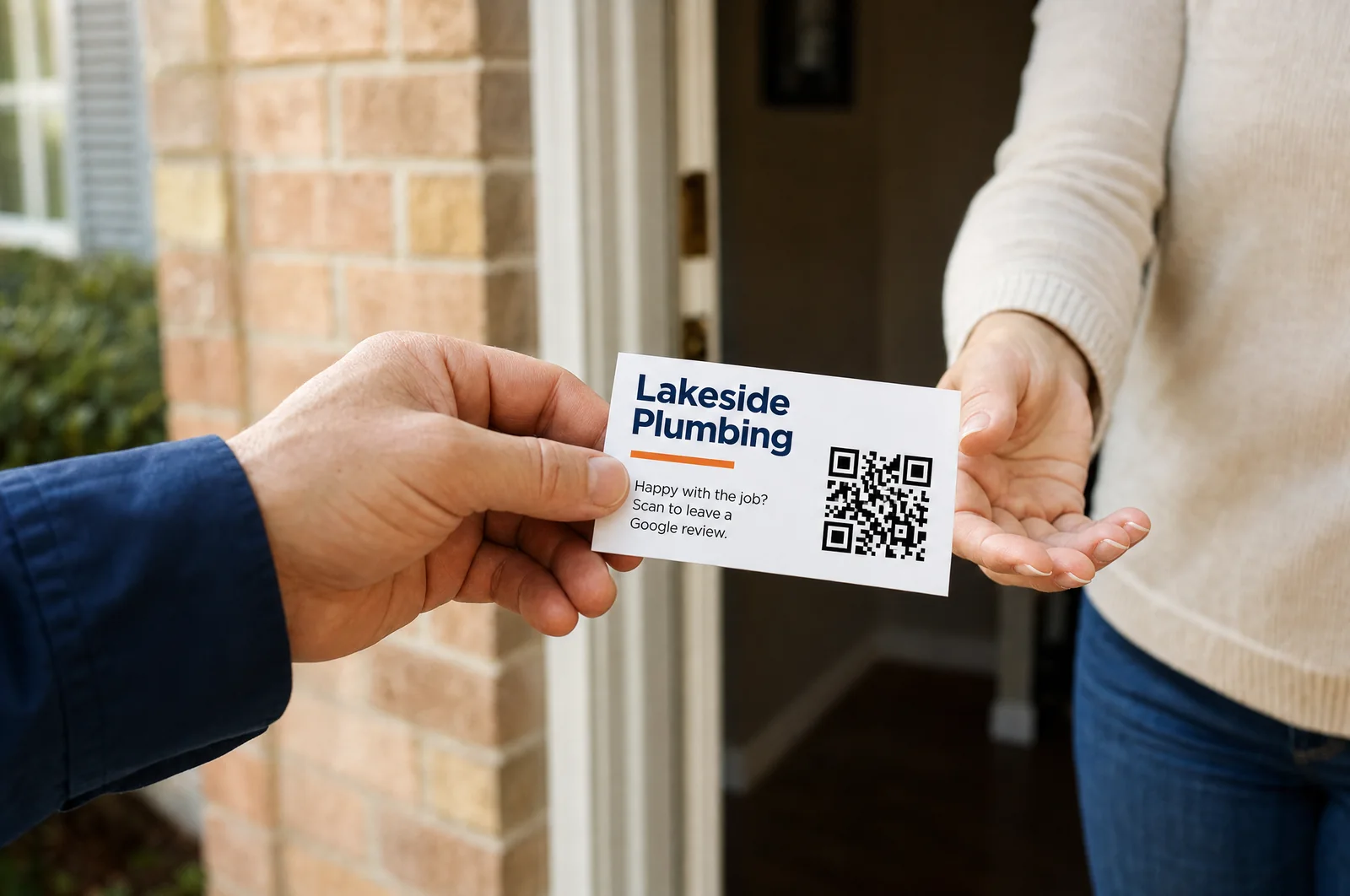 A contractor hands a business card to a homeowner at the front door